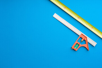 Technician's set of tools on solid coloured blue background including tape measures and carpenter...