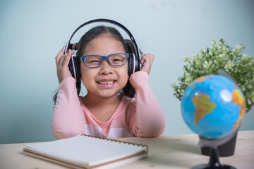 Concept learning online social distance. Student Asian kids girls wearing glasses, headphones smile happily Listen to online lessons from teachers. learning from home in the room personal.