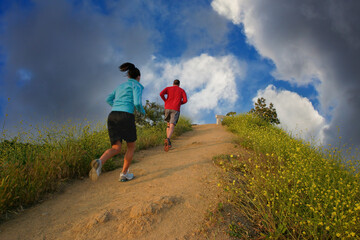 Couple running uphill on a beautiful trail in Runyon Canyon Park, Hollywood Hills, California USA