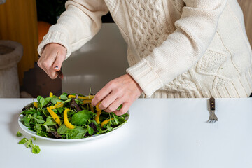 middle aged blonde woman preparing green salad in the kitchen, close-up