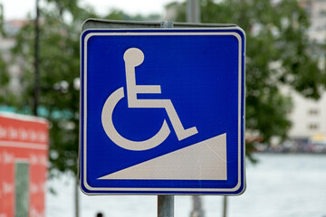 Disabled Ramp Access Sign in the city. Green foliage background on the background.