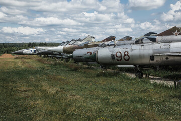 Old rusty abandoned planes stand on the grass under the open sky. Vintage military aircraft. Abandoned military equipment.