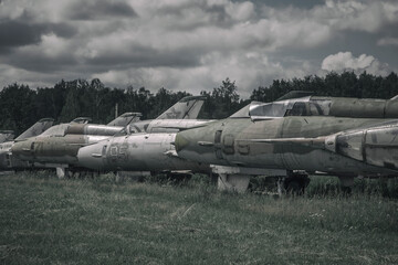 Fototapeta na wymiar Old rusty abandoned planes stand on the grass under the open sky. Vintage military aircraft. Abandoned military equipment.