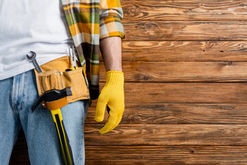 cropped view of handyman in tool belt and work glove on wooden background, labor day concept