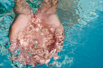 Female hands cupped together submerged in clean clear blue water