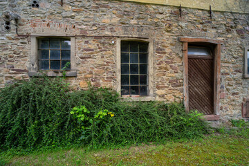Lost place, old stone building with wooden door and transom window.
