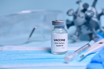 Two Bottle of Covid-19 vaccine to immunize from the Delta Variant Coronavirus, syringe , face mask,body thermometer and protective glasses on blue background.The concept of medicine, healthcare