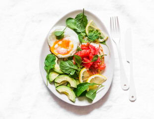 Delicious breakfast, brunch - poached egg, salmon, avocado, arugula salad on a light background, top view