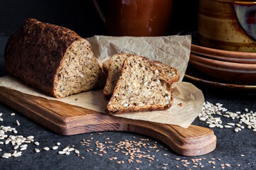 Bread with sunflower and flax seeds on a wooden cutting board on a black background