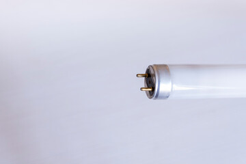 End of a long glass lamp with contacts on a solid background and free space for text beside it.