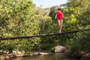 Lady in red standing on small make shift bridge over the Rio das Almas in the interior of Brazil