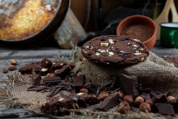 Chocolate cookies with hazelnuts , cocoa and pieces of dark chocolate on the rustic kitchen table