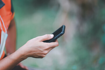 Young woman using a smartphone with a technology device with natural green background