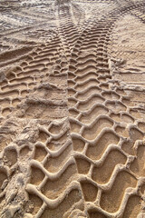 Goldener feiner Sand mit reliefartigen Reifenspuren. Contrastreiche Schatten auf Sandstrand. Schwere Werkzeugmaschinenfahrzeuge hinterließen tiefe Spuren im Sand. Silicon Silizium Silicium carbide