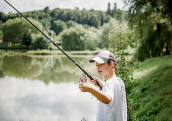 A boy holding a fishing rod and fishing in the lake, summer activities and hobbies for children