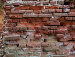 A dilapidated red brick wall destroyed by time and external factors.