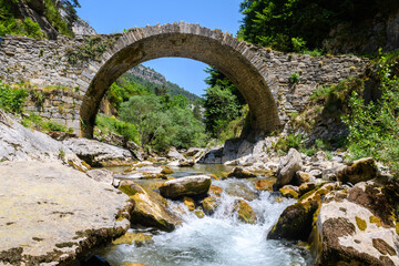 views of old roman bridge ruins crossed by a river in pyrenees, Spain