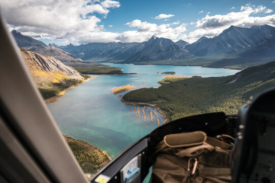 Inside of helicopter flying on rocky mountains with turquoise lake and blue sky