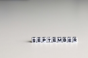 SEPTEMBER is a word written on a white block. SEPTEMBER is the word for your design, concept. Beautiful bokeh in the background