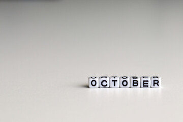 OCTOBER is a word written on a white block. OCTOBER is the word for your design, concept. Beautiful bokeh in the background