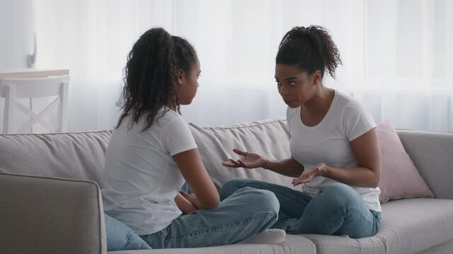 Young annoyed african american woman quarreling with grumpy black girl teenager, telling about her bad behavior
