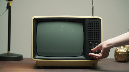 Close-up of turning on old retro television with antenna on grey background, channel setting. Broken old-fashioned TV with noise screen on table, bad signal reception, cinematography concept.