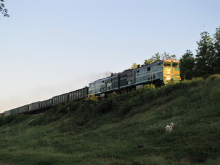 Obraz premium An old Soviet train. A long train train. Railway in the village. A train leaving for the sunset