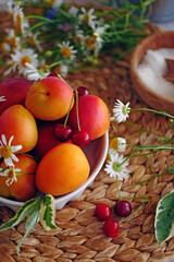 Naklejka na ściany i meble Harvest ripe fruit background. On the table are apricots and peaches, cherries, wildflowers, copy space