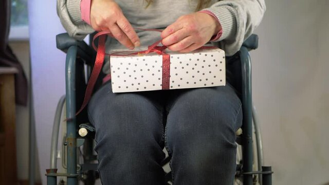 Woman in wheelchair opening wrapped gift