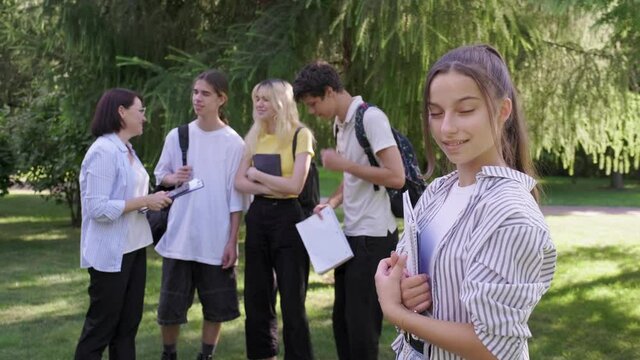 Female student 14, 15 years old with textbooks backpack, in school park