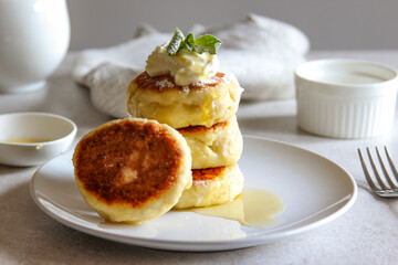 Sweet cheese pancakes with honey and cream on a white plate. Homemade recipe cheesecakes.