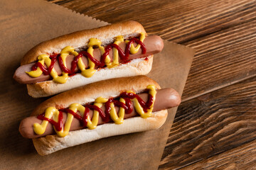 top view of delicious hot dogs and craft parchment on wooden surface