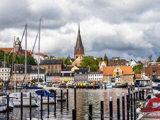 Obraz premium Sail boats in the port of Flensburg, St. Jorgen's Church in the background. Schleswig-Holstein in Germany