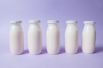 Bottles with probiotics and prebiotics dairy drink on light purple background.