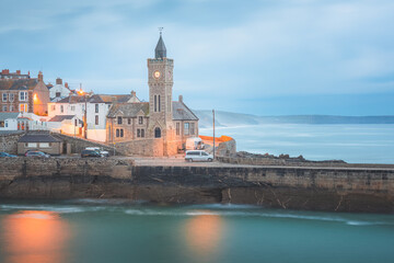 Moody, atmospheric night view of the pier and church clock tower at the quaint seaside village of Porthleven, Cornwall, England, UK. - obrazy, fototapety, plakaty