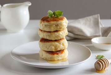 Sweet cheese pancakes with honey on a white plate. Homemade recipe cheesecakes.
