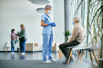 Senior man with neck injury and radiologist wearing face masks while communicating in waiting room...