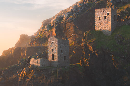 Close-up detail of old stone ruins of engine houses at Botallack mines on the Atlantic coast of Cornwall, England, UK during golden hour at sunset or sunrise.