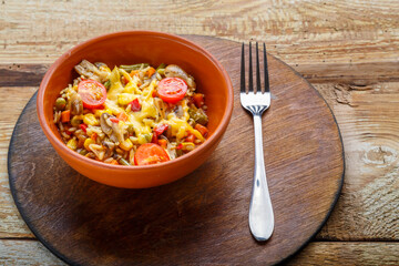 Risotto with mushrooms in a plate on a wooden background on a wooden round stand next to a fork.