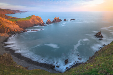 Dramatic seascape landscape of rock formations with golden hour sunset or sunrise light of Screda Point at Hartland Quay on the North Devon coast in England, UK. © Stephen