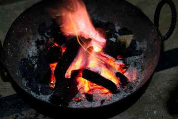 Burning charcoal in an iron stove for home heating. Red burnt charcoal and ashes to warm the room.