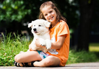 portrait child girl hugging puppy in summer