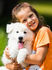 child girl hugging puppy in the park