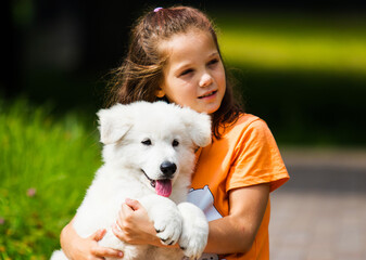 portrait child girl hugging puppy in summer
