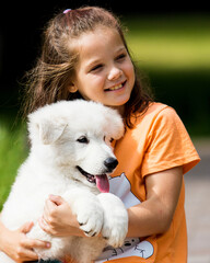 child girl hugs puppy in summer