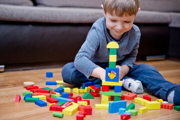 A young builder. kid building city from wooden blocks. Kids Play Room. Development and Construction Concept. Toy to learn stimulates imagination, creativity, hand-eye coordination.