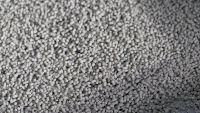 Plastic pellets jump on the grid of the vibrating table. Production of granular polyethylene.