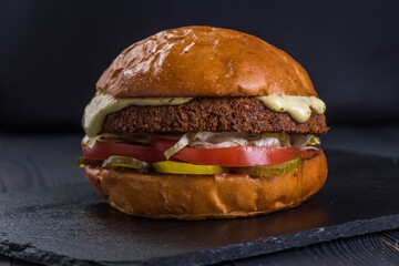 Vegan burger. Falafel and craft bun on a stone tray.