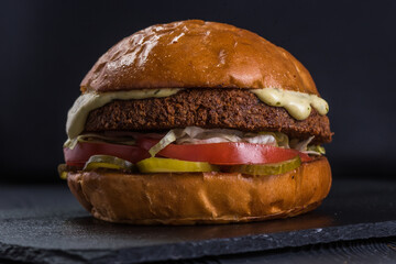 Vegan burger. Falafel and craft bun on a stone tray.