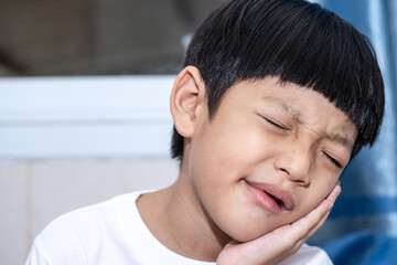 Asian little boy is doing a terrible toothache. Portrait a little boy suffering from toothache. Oral Care Concepts